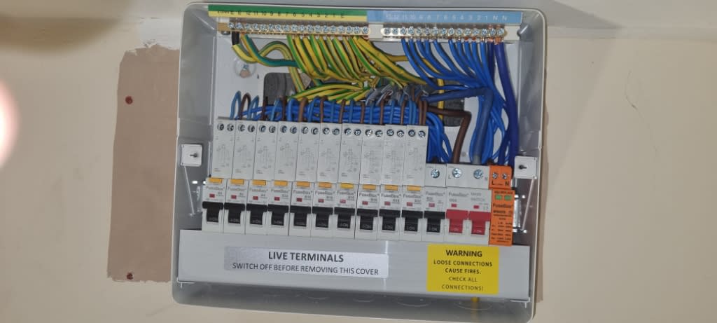 Consumer unit with its cover removed, showing circuit breakers and internal wiring